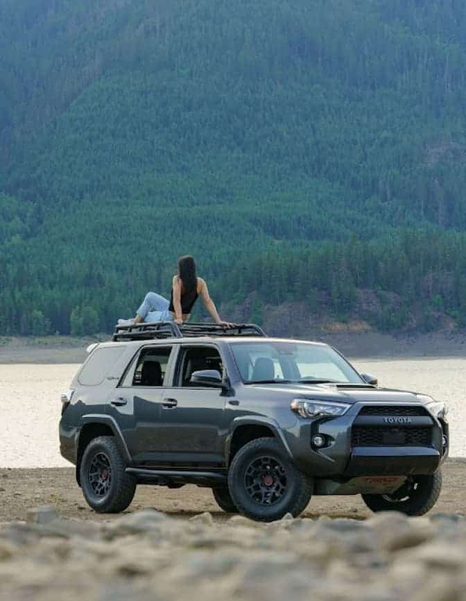 woman seating on truck next to lake